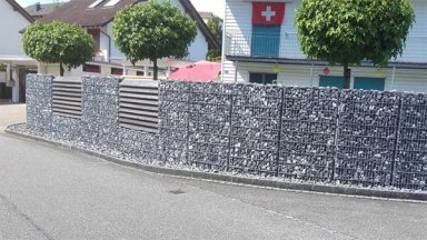 Gefüllte Steinkörbe als Gabionenmauer für kompletten Sichtschutz für den Garten